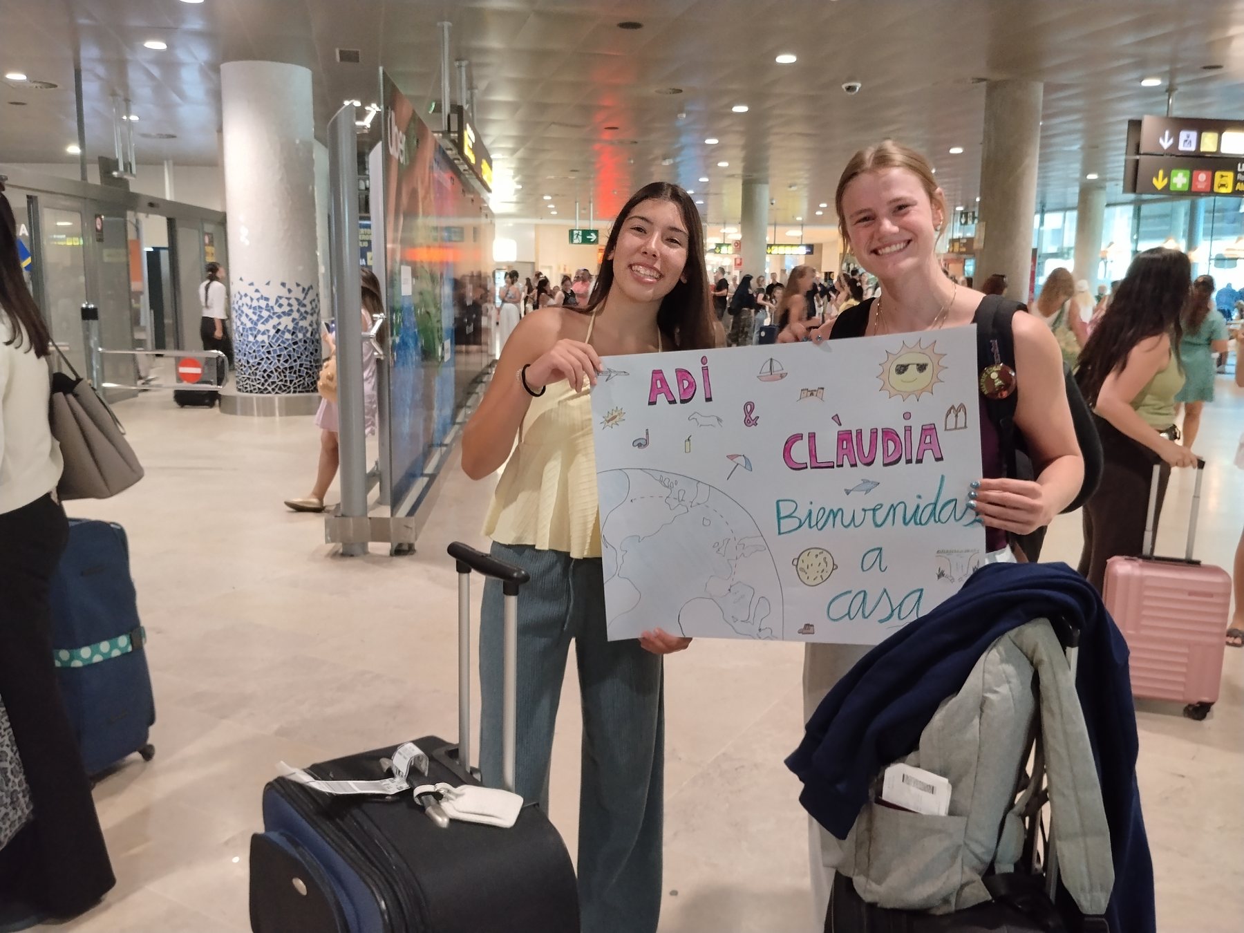Addilyn and her exchange partner at the Valencia airport, holding a hand-drawn welcome sign
